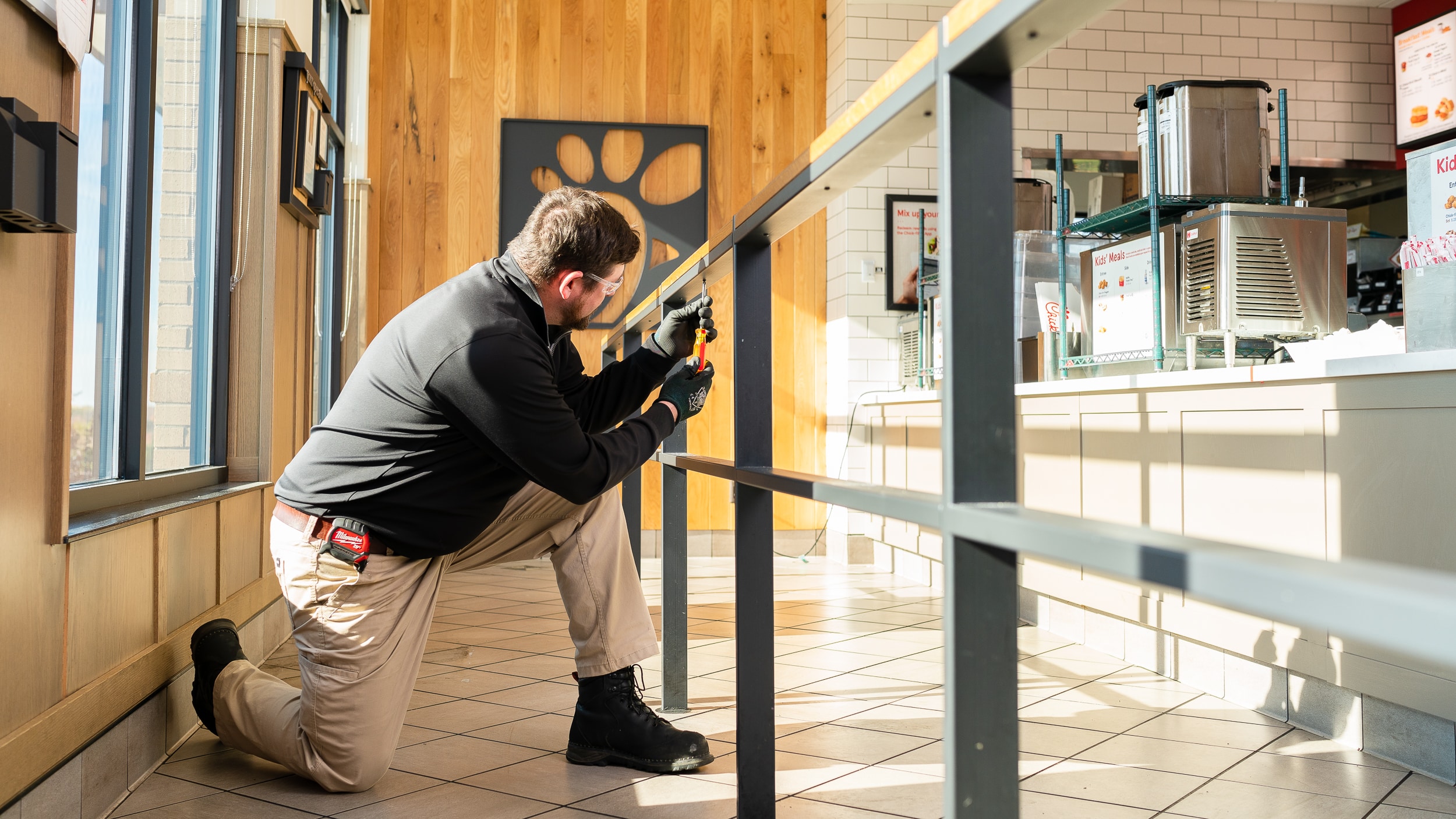 a construction worker finishing of the railing inside a Chick-fil-A